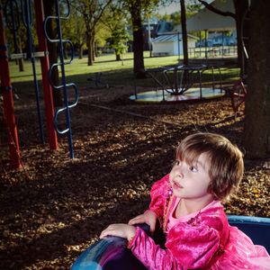 Girl in pink dress on slide at park