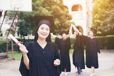 Cheerful student with clenched fist wearing graduation gown