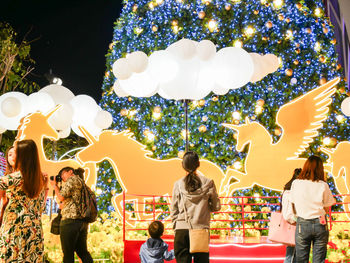 People standing in amusement park against clear sky at night