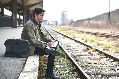 Man sitting at railroad station during winter