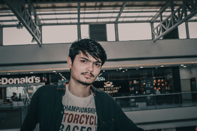 Portrait of young man standing against ceiling