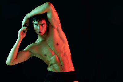 Portrait of young man standing against black background