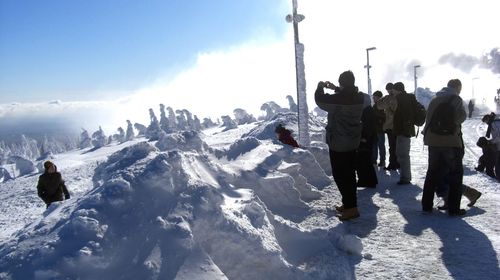 Rear view of people on snowcapped mountain against sky