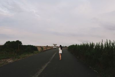 Woman standing on road against sky