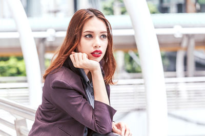 Thoughtful young businesswoman standing on elevated walkway 