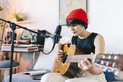 Female guitarist wearing knit hat while playing guitar at studio