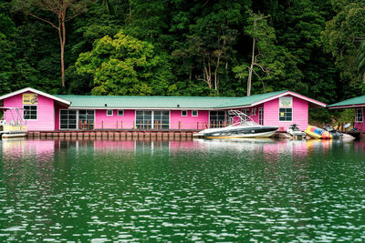 Houses by lake against trees