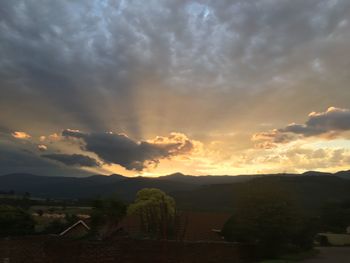 Scenic view of landscape against dramatic sky during sunset