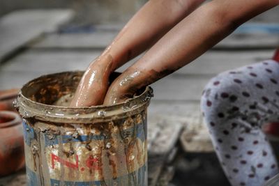 Cropped hands of woman in wet muddy bucket