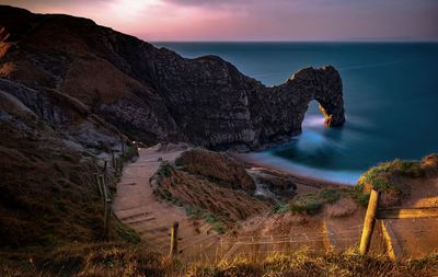 Rock formations by sea against sky during sunset