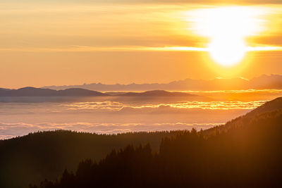 Scenic view of silhouette mountains against orange sky