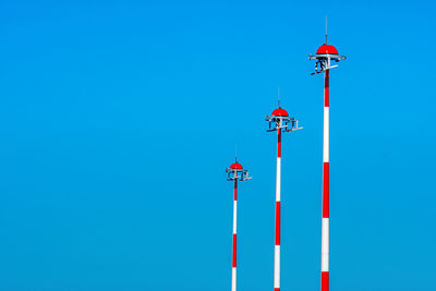 Row of the airport lamp posts with alternate red and white painting on blue sky background