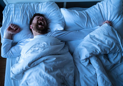 High angle view of man sleeping on bed