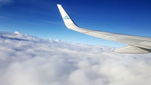 Airplane flying over clouds against blue sky