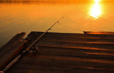 Fishing rod at pier during sunset