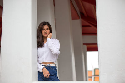 Portrait of teenage girl standing by architectural column