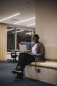 Mid adult businesswoman working on laptop in office at night