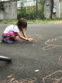 Girl sitting on road in city