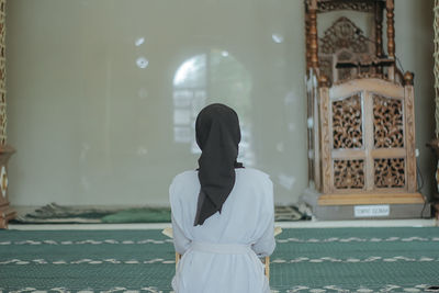 Rear view of woman standing against building