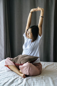 Midsection of woman sitting on bed at home