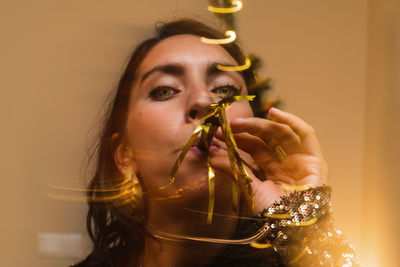 Charming female using party horn while having fun at home during christmas party and looking at camera