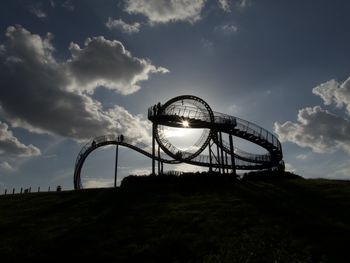 Low angle view of silhouette ferris wheel on field against sky