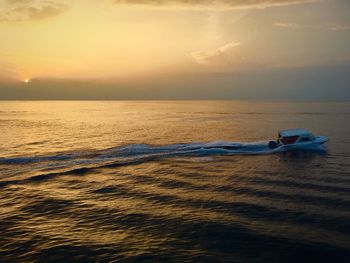 Boat in sea against sky during sunset