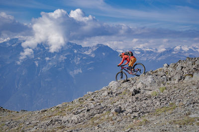 Man riding bicycle on mountain against sky