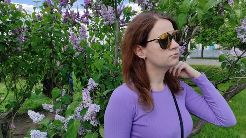Beautiful young woman wearing sunglasses against white flower
