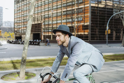 Side view of young man riding bicycle in city