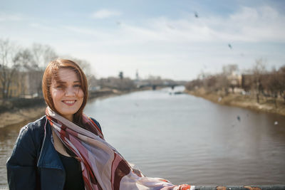 Portrait of smiling young woman standing against sky