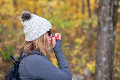 Portrait of woman wearing hat against trees in forest