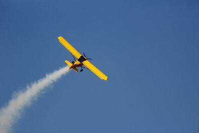 Low angle view of airplane flying against clear blue sky