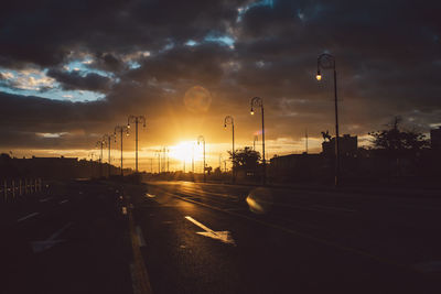 Cars on road against sky during sunset