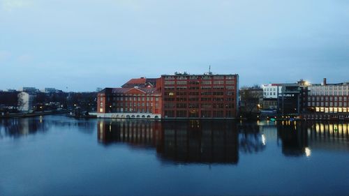 Buildings by river against sky