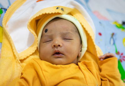 Cute newborn baby sleeping in yellow dress from top angle