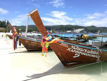 Close-up of boats moored on beach against sky