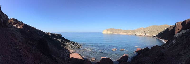 Panoramic shot of rocky beach against clear blue sky