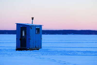 Built structure on snow covered landscape against sky