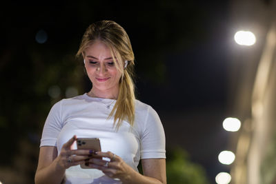 Woman using a smartphone at night time on the street. mobile phone, technology, urban .