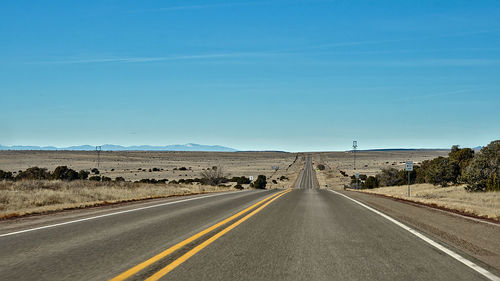 Empty road against clear blue sky