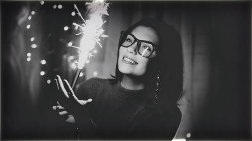 Smiling young woman with illuminated firework at night