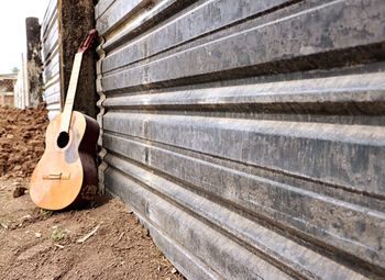 Close-up of guitar on field by wall