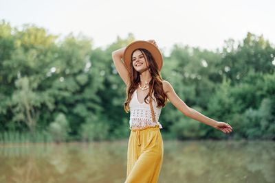 Young woman standing against trees