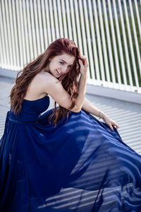 Smiling woman in dress sitting on bridge 