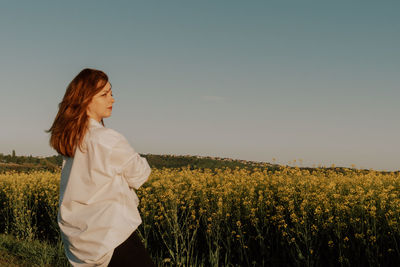 Young woman standing on field against clear sky