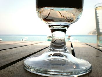 Close-up of water on table by sea against sky