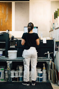 Rear view of female employee using computer in store