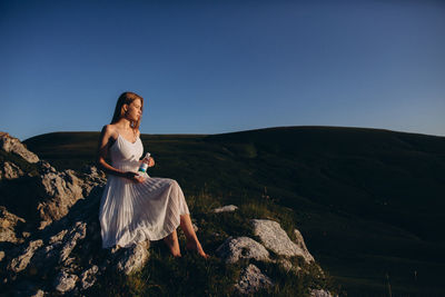 Young woman standing on mountain against clear sky