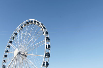 Low angle view of ferris wheel against clear blue sky